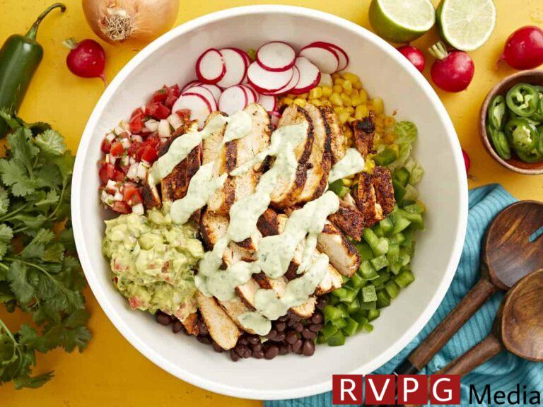 creamy avocado dressing drizzled over santa fe salad in a large white bowl.