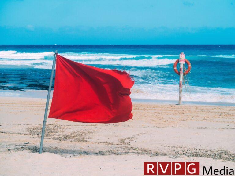 Red flag and lifebelt attached to pole on the beach. No swimming.