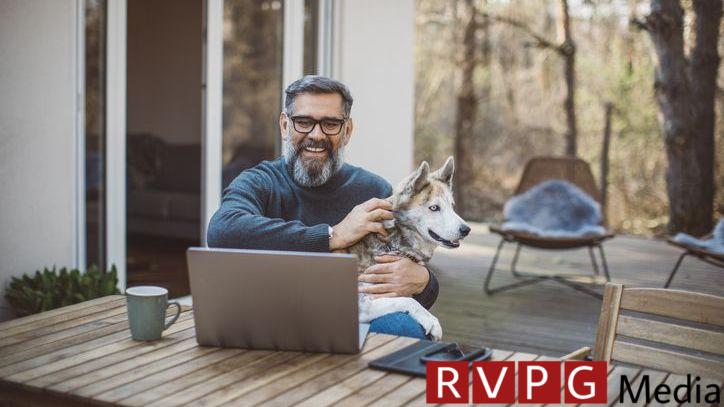 A man looks over his retirement portfolio while sitting on his deck with his dog.