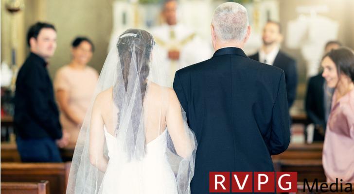 A father walks his daughter down the aisle during her wedding.